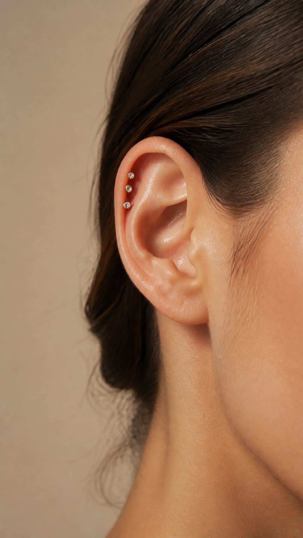 Close-up of an ear with three crystal studs arranged along the forward helix.