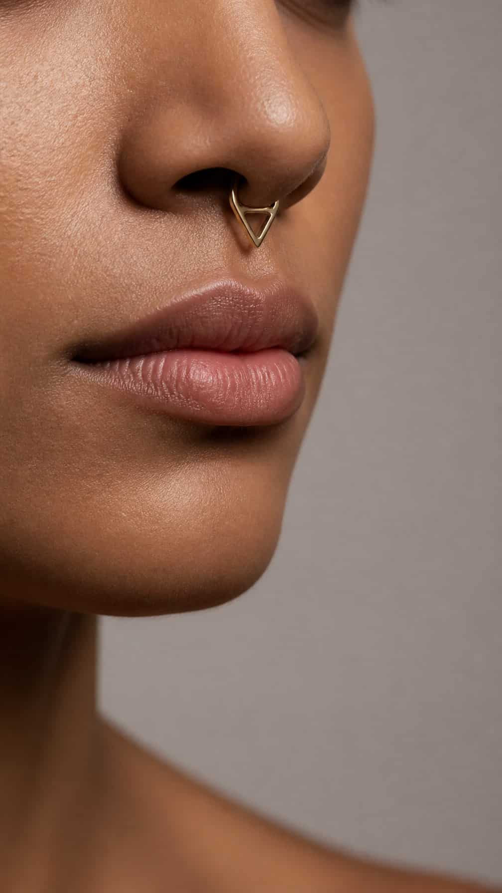 Close-up portrait showing a polished triangular septum clicker piercing.