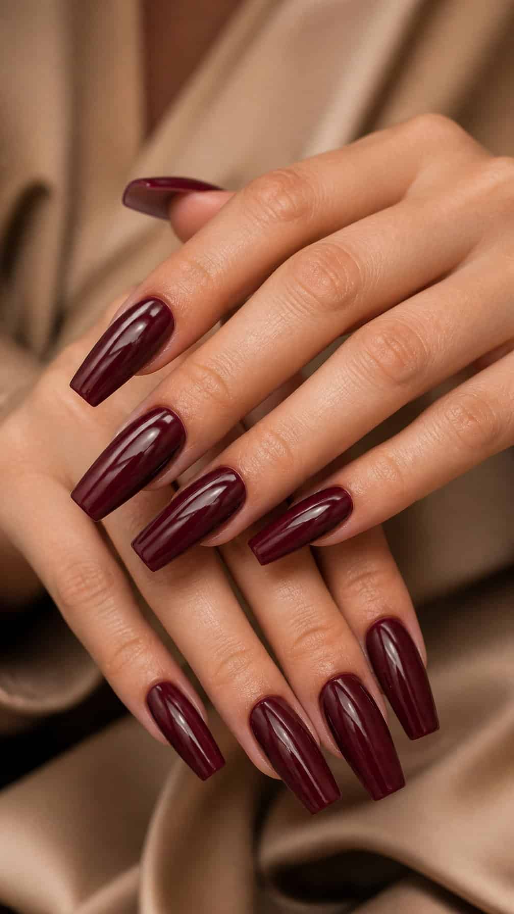 Close-up of hands with long glossy burgundy coffin-shaped nails.