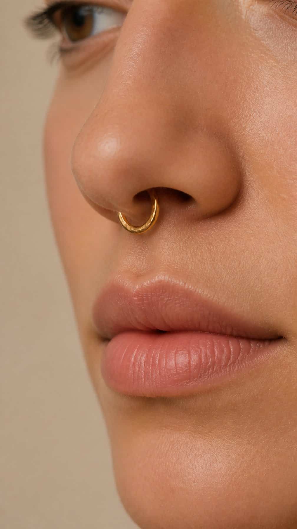 Close-up of a person wearing a textured gold septum ring.