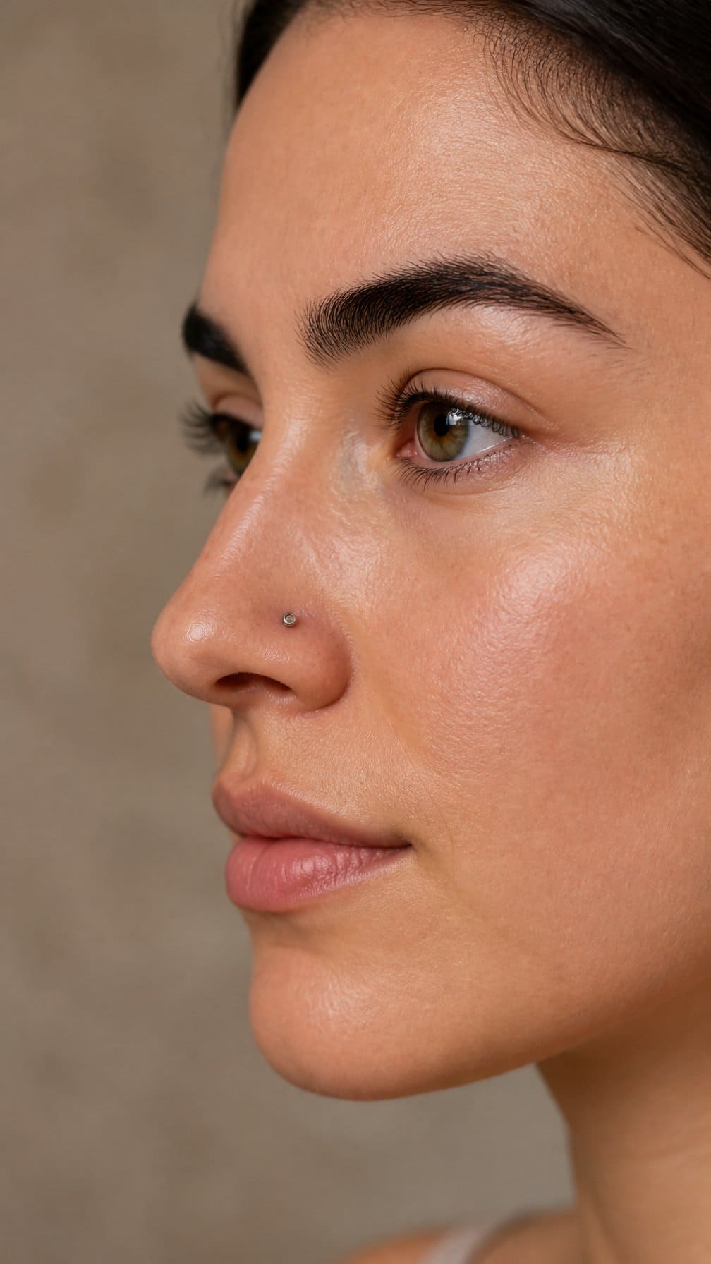 Side-profile portrait of an adult wearing a small high nostril stud.