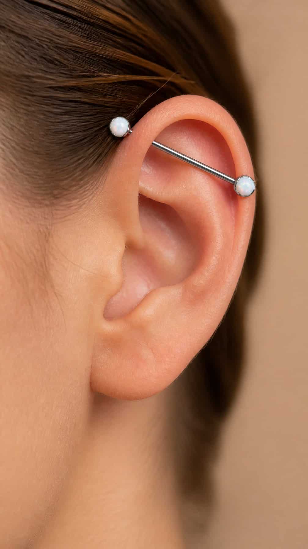 Close-up of an ear wearing an industrial barbell piercing with two opal ends.