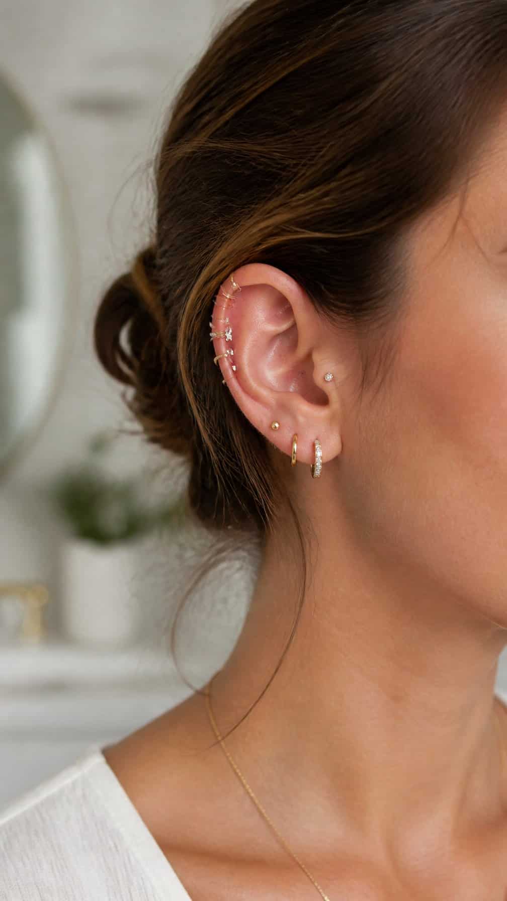 Close-up of an ear with several delicate helix piercings and polished jewelry.