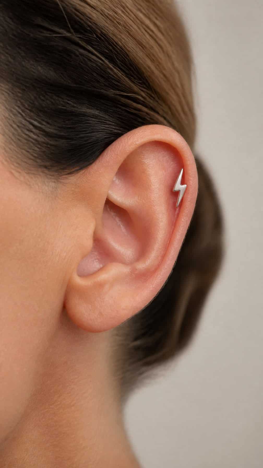 Close-up of an ear wearing a lightning-bolt-shaped helix earring.
