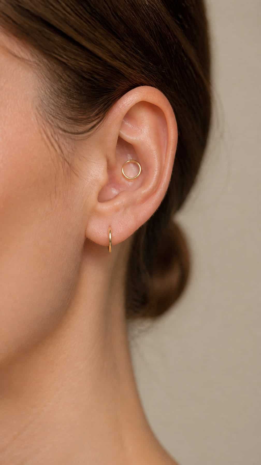 Close-up of an ear showing a lobe piercing and a daith piercing with small hoops.