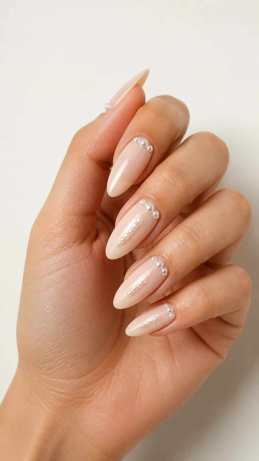 A hand with long almond-shaped nails decorated with small raised pearls.