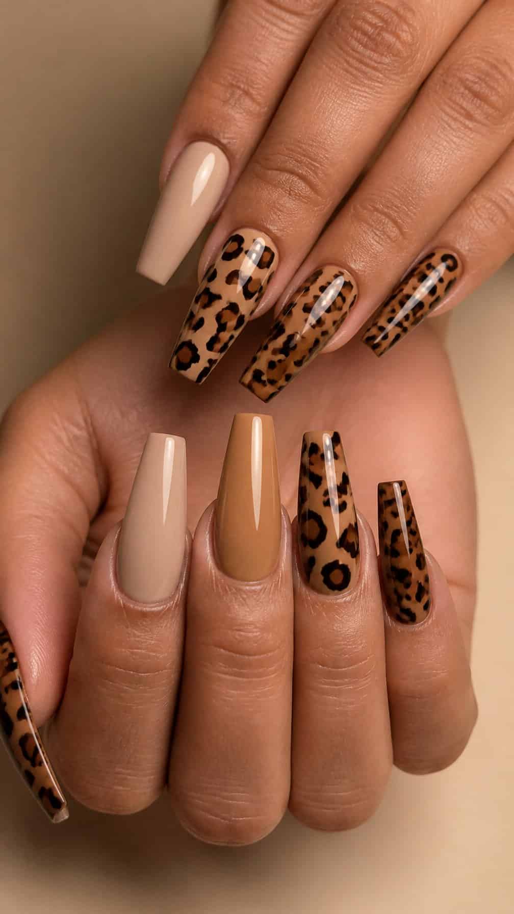 A hand displaying long coffin-shaped nails with a leopard-print manicure.