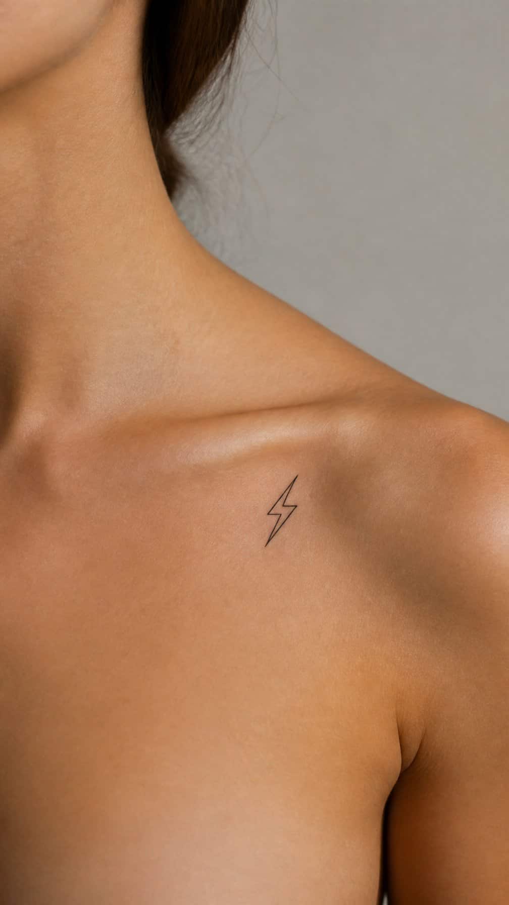 Close-up of a small lightning bolt tattoo near the outer collarbone.