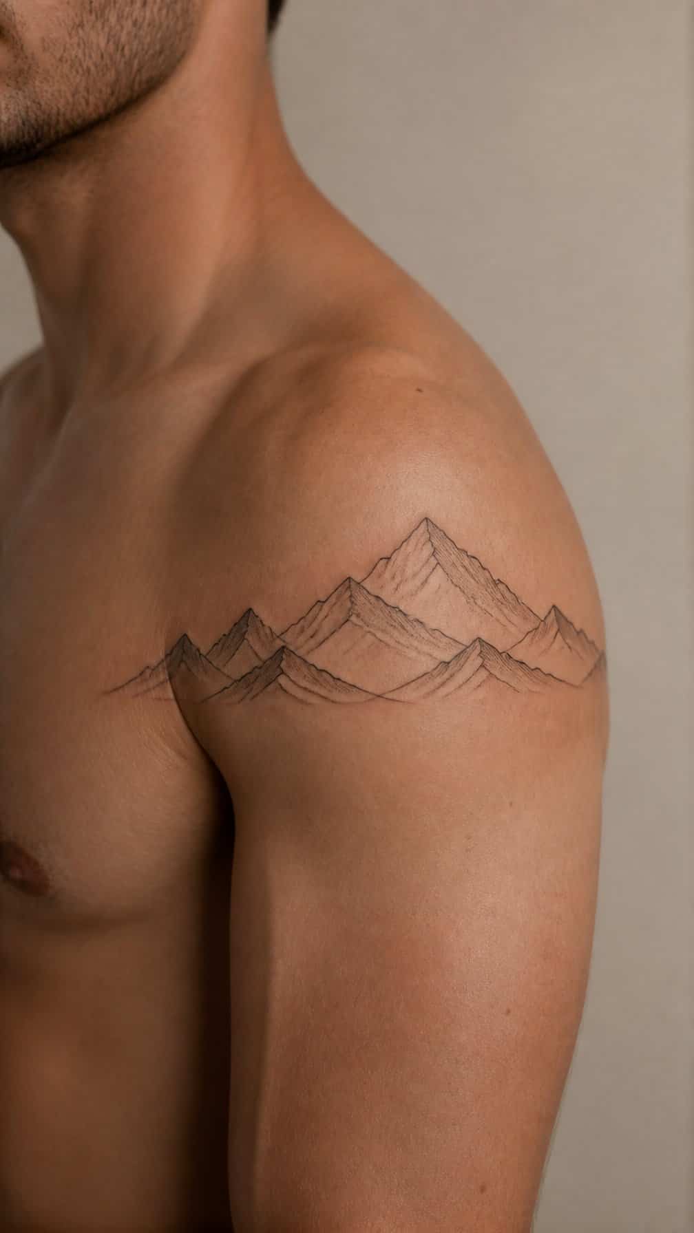 A minimalist mountain range tattoo wraps around a person’s shoulder and upper arm.