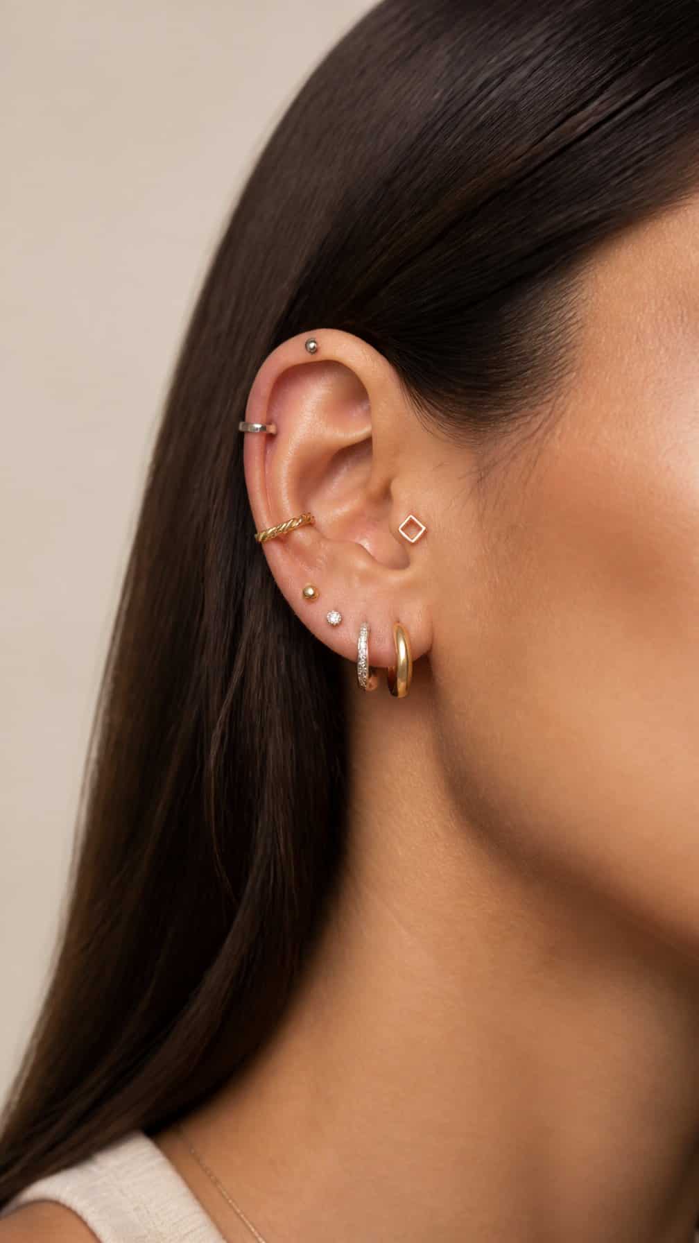 Close-up of an ear wearing a curated mix of gold, silver, and rose-gold piercings.