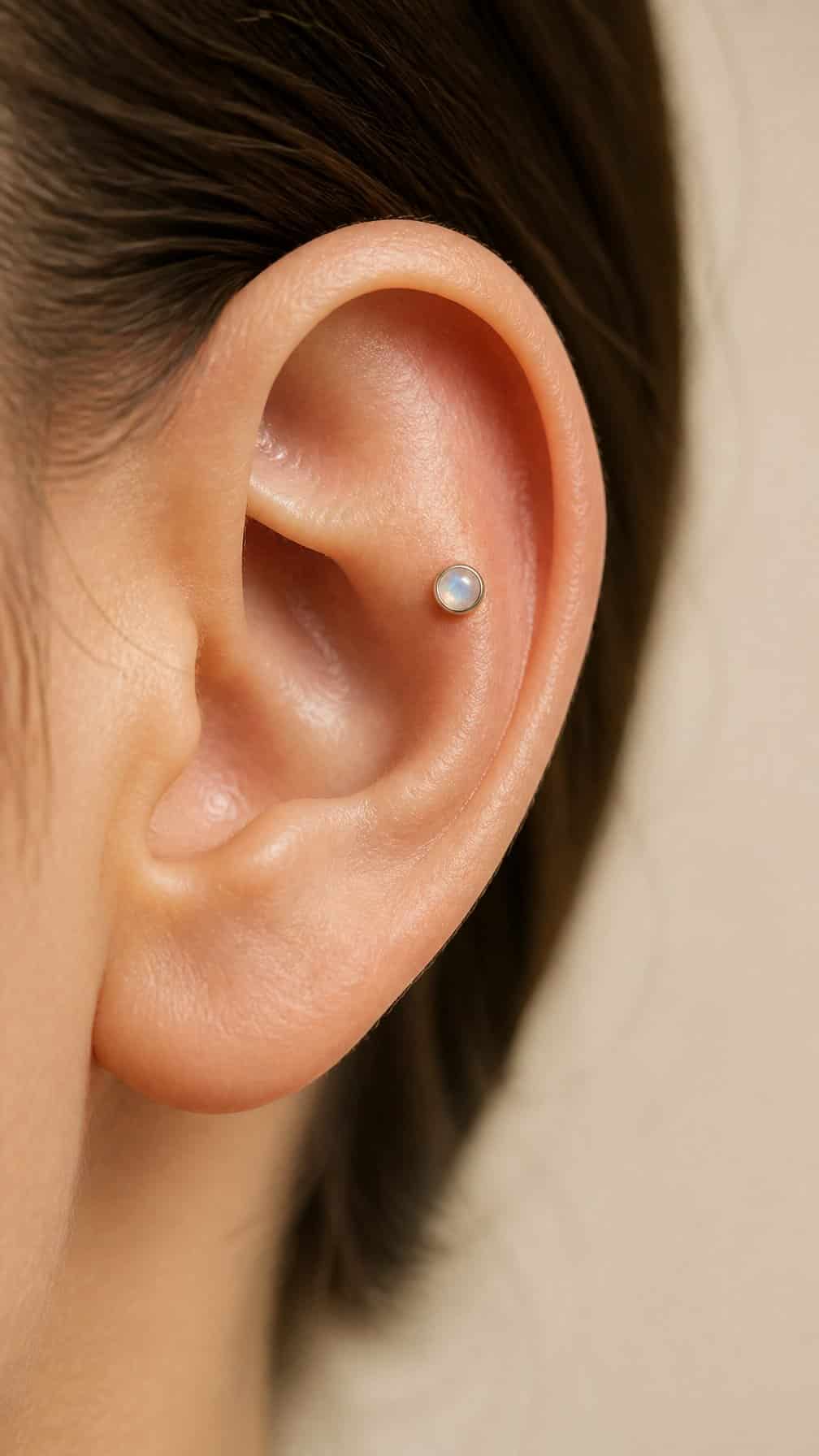 Close-up of an ear wearing a small moonstone conch piercing.