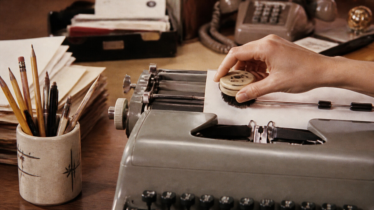 Hand using a round typewriter eraser and brush on a manual typewriter