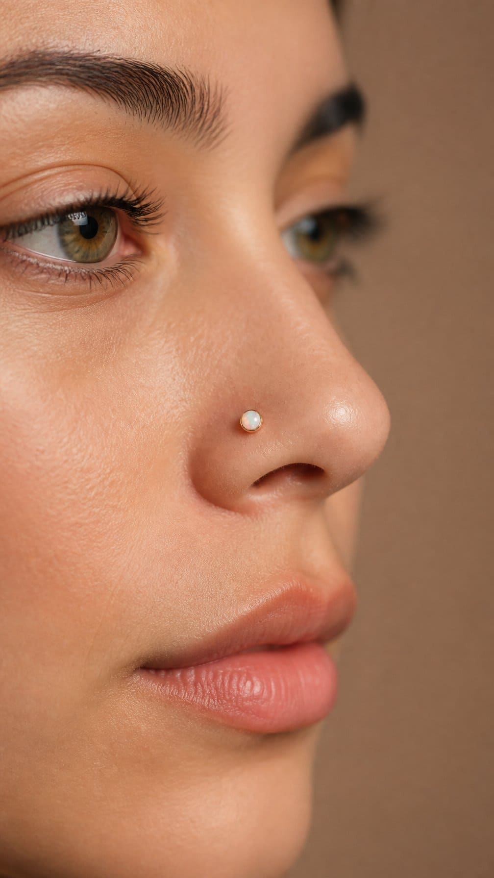 Close-up of an adult wearing a small iridescent opal nostril stud.