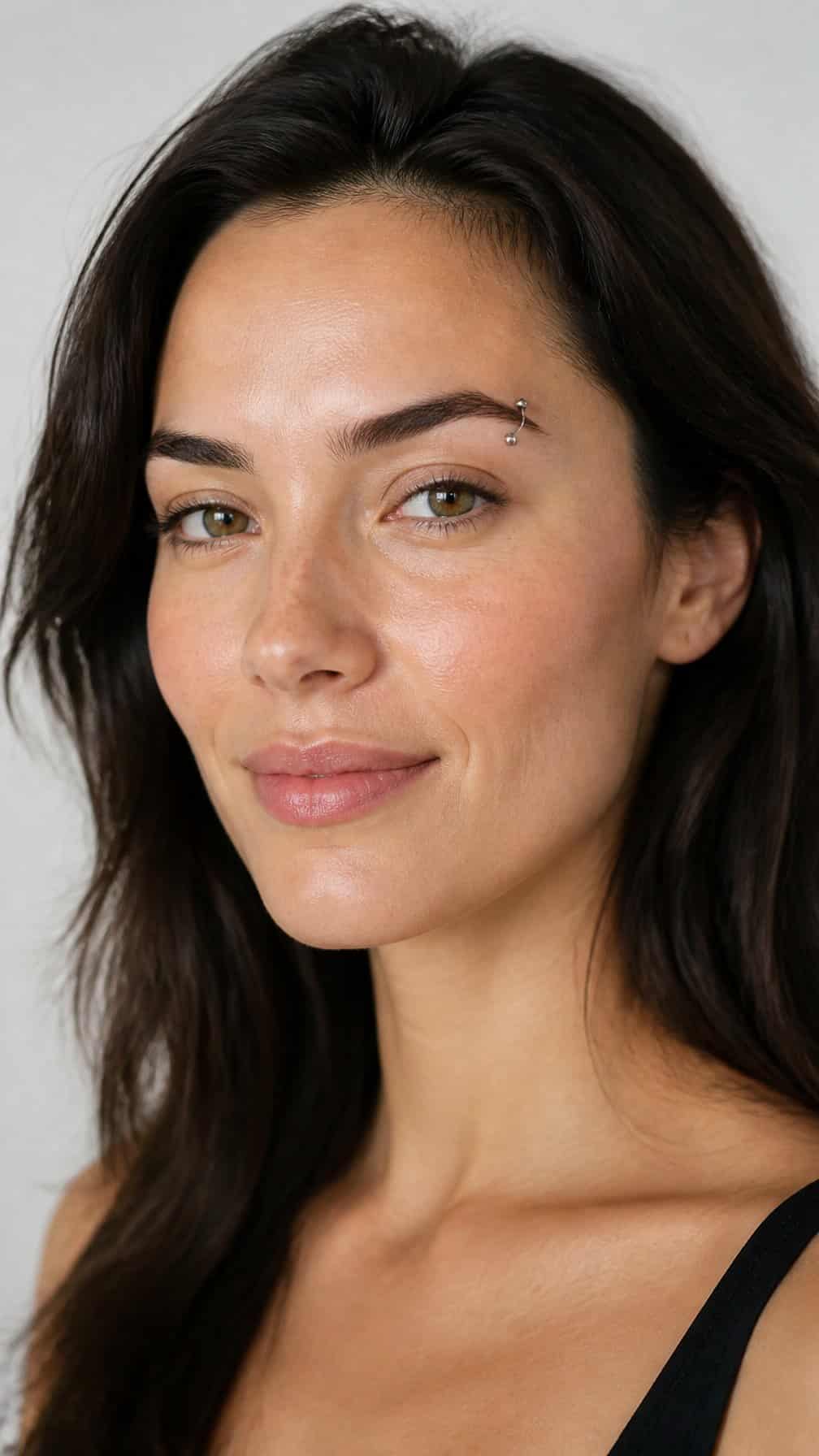 Close-up portrait of a person with a heart-shaped face and a small outer eyebrow piercing.