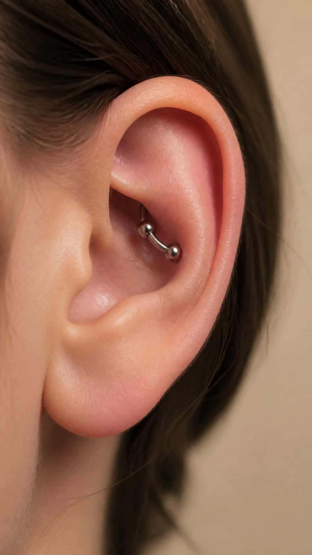 Close-up of an outer ear featuring a curved barbell conch piercing.
