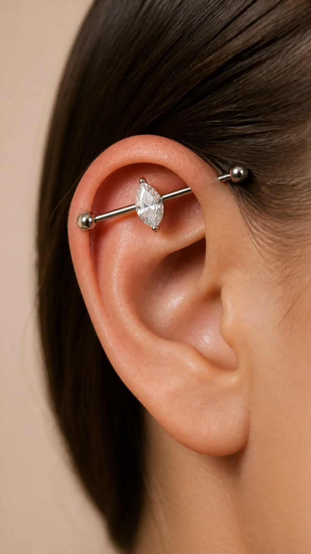 Close-up of an ear with a pear-shaped gemstone industrial piercing.