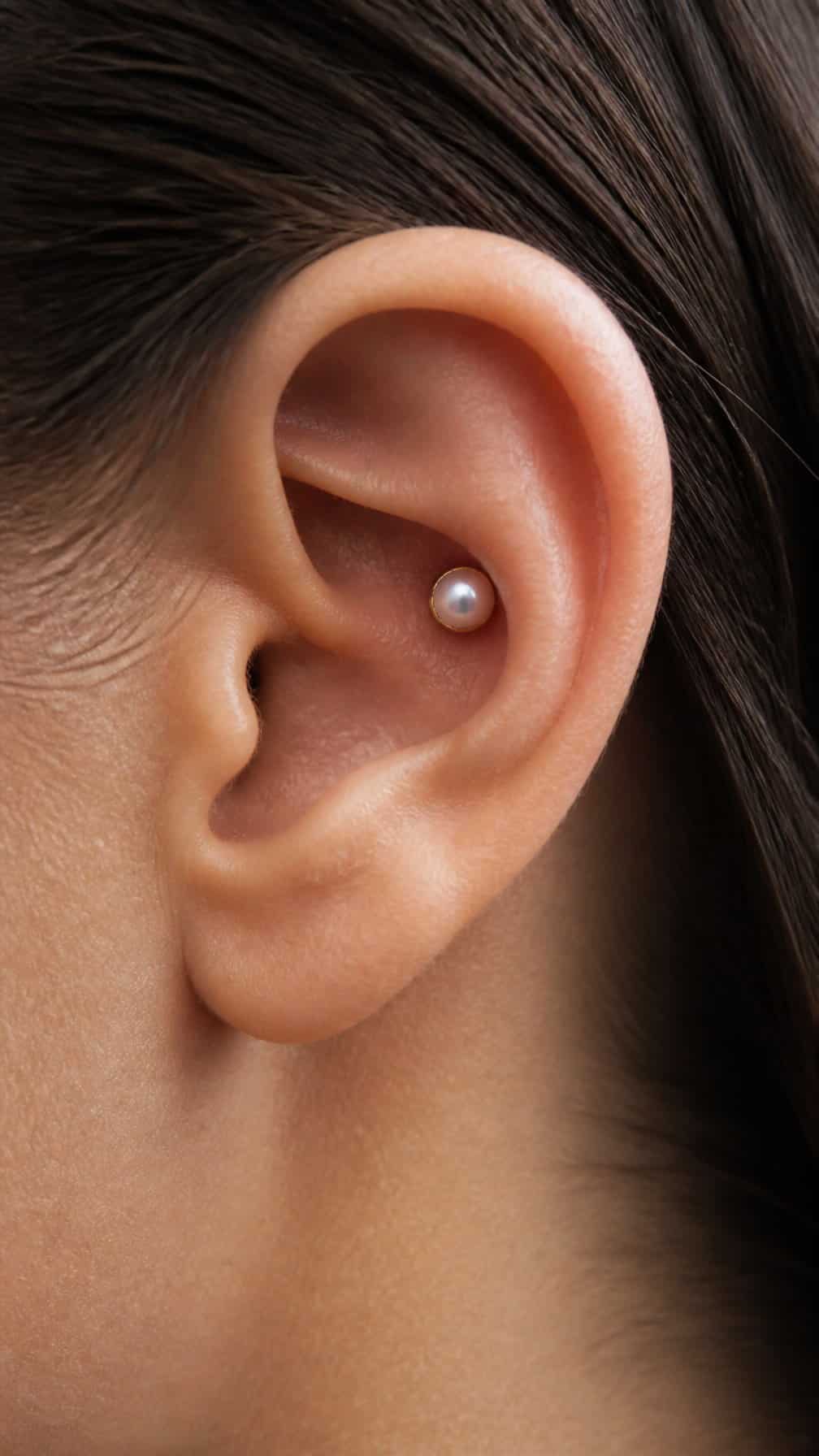 Close-up of an ear wearing a small pearl conch stud.
