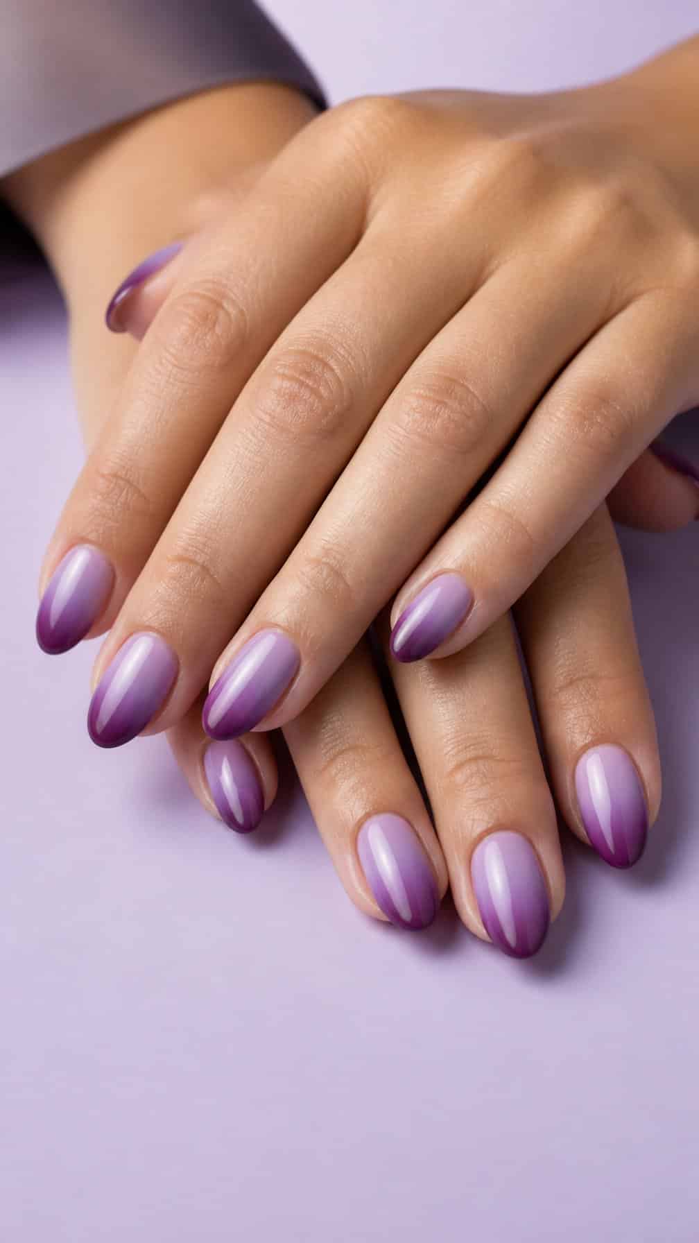 A close-up of hands with glossy plum-to-lavender ombre manicure.