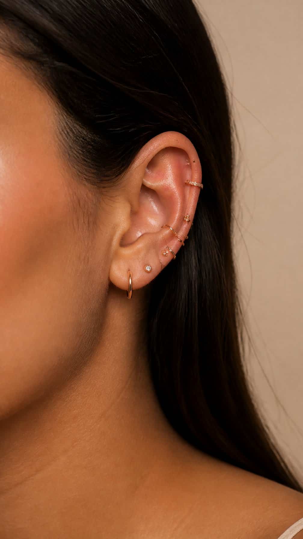 Close-up of an ear with several coordinated rose-gold helix piercings.