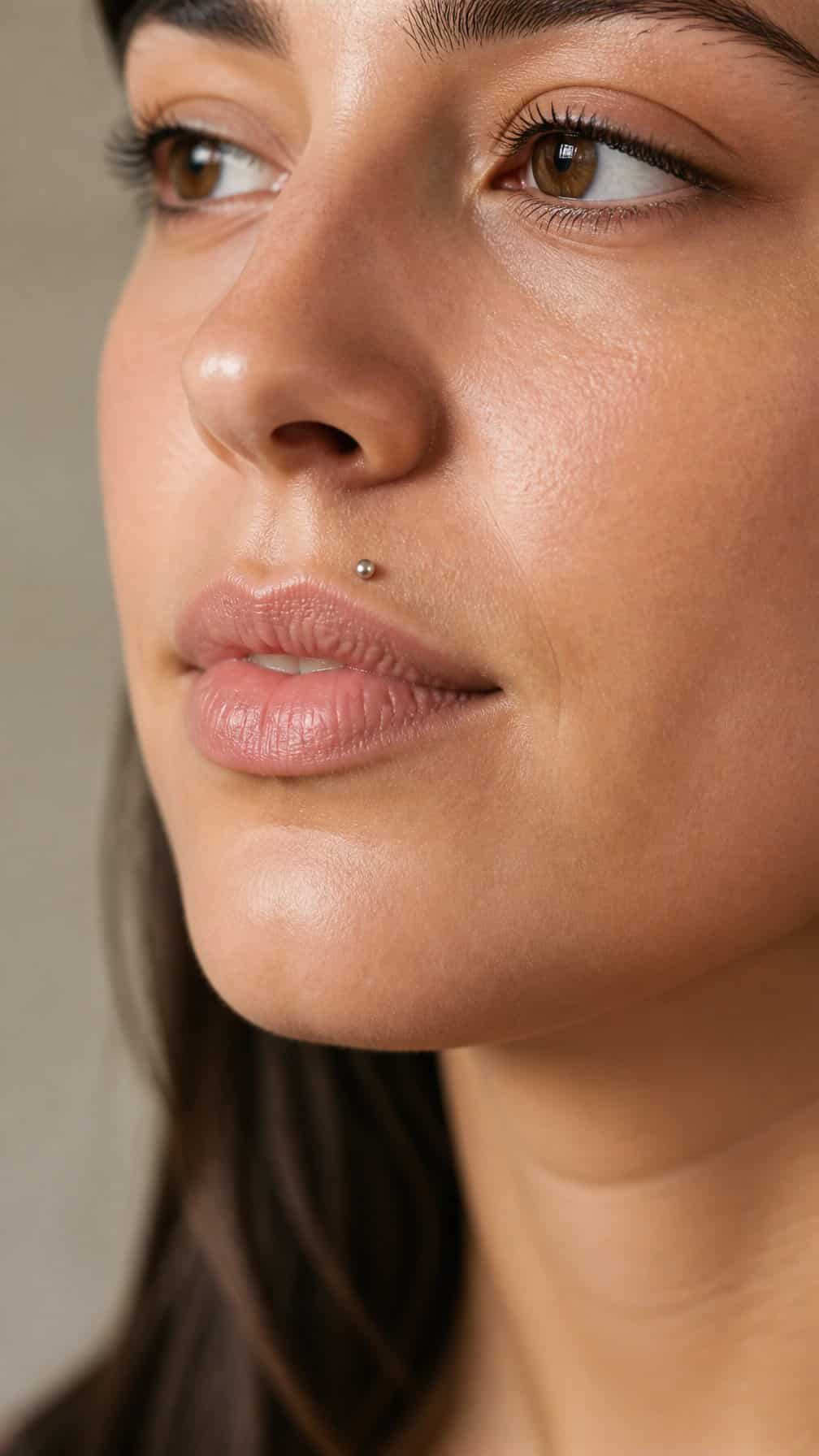 Close-up of a person wearing a small rose-gold stud above the upper lip.