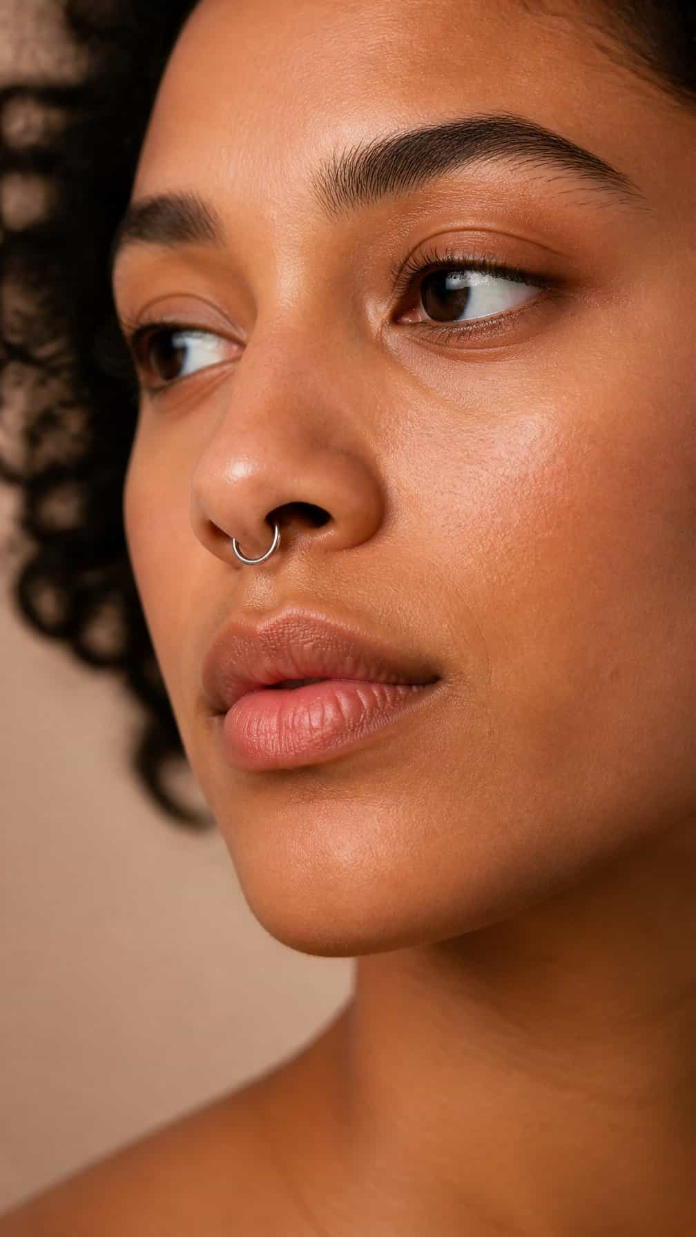 Close-up portrait of an adult wearing a delicate clicker ring septum piercing.