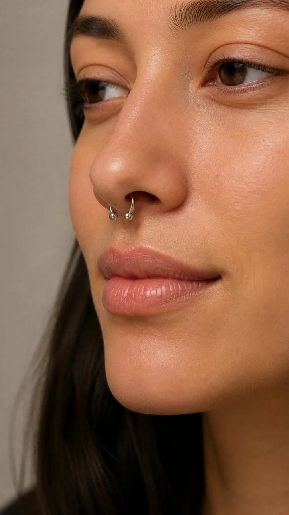 Close-up of an adult wearing a polished horseshoe barbell septum piercing.
