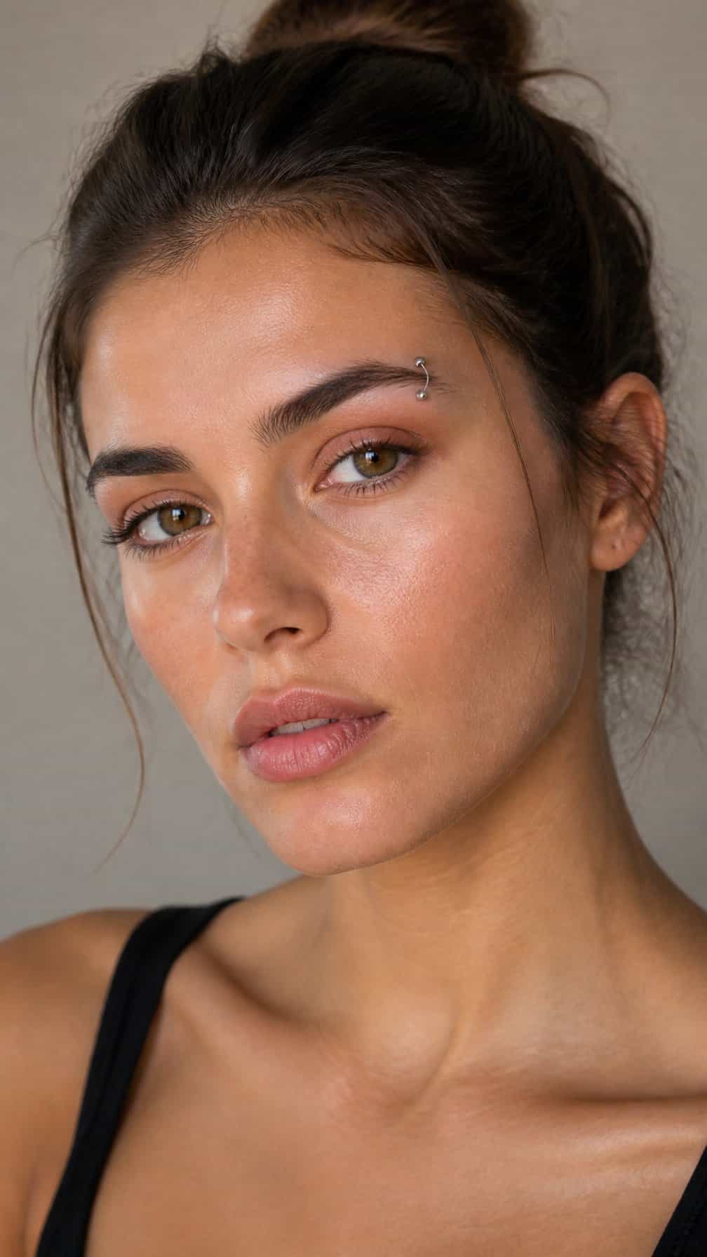 Close-up portrait of a person wearing a small silver eyebrow piercing.