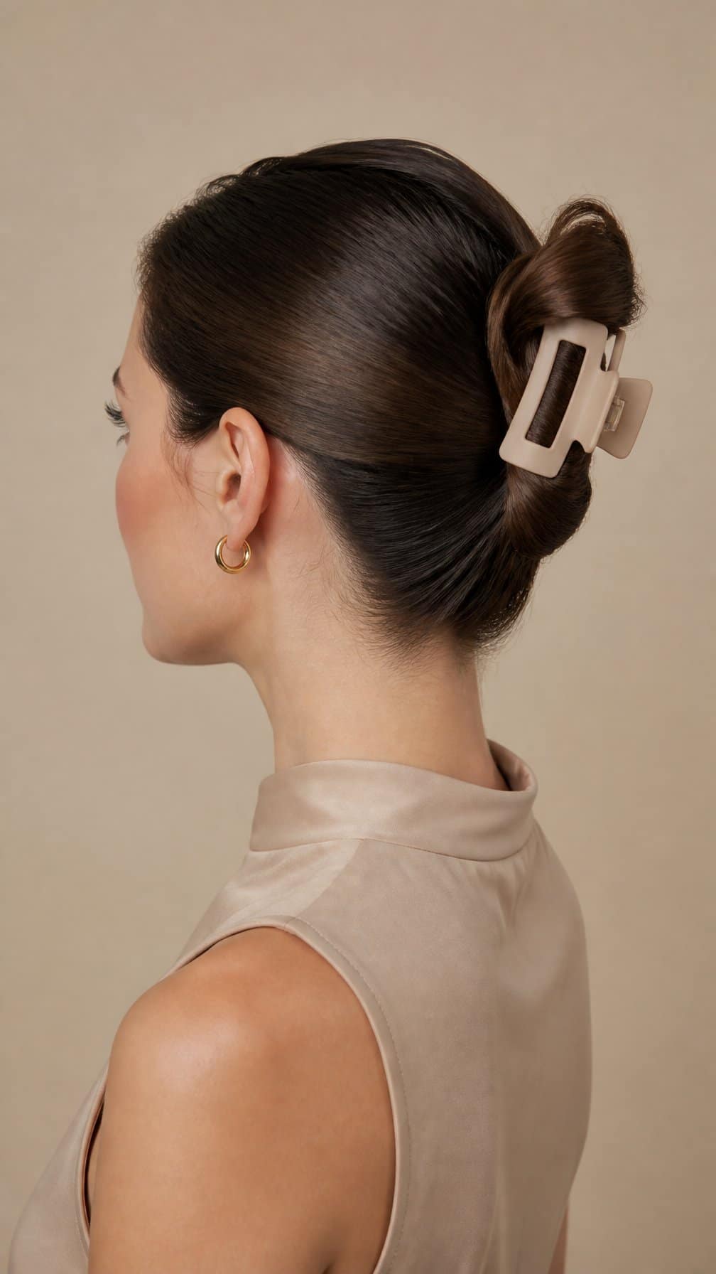 Woman with her hair smoothly gathered into an updo secured at the back with a claw clip.
