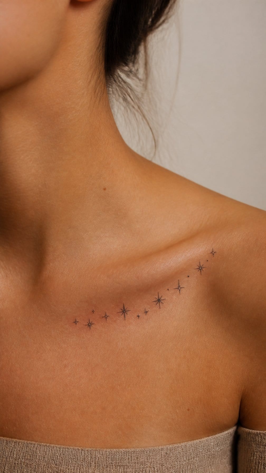 A small cluster of star tattoos curves gracefully along a person’s collarbone.