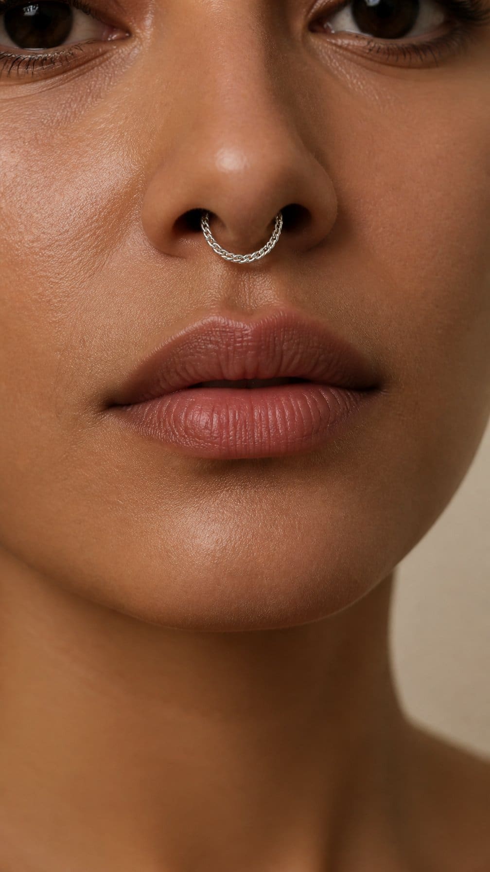 Close-up of a person wearing a delicate snake-chain septum ring.