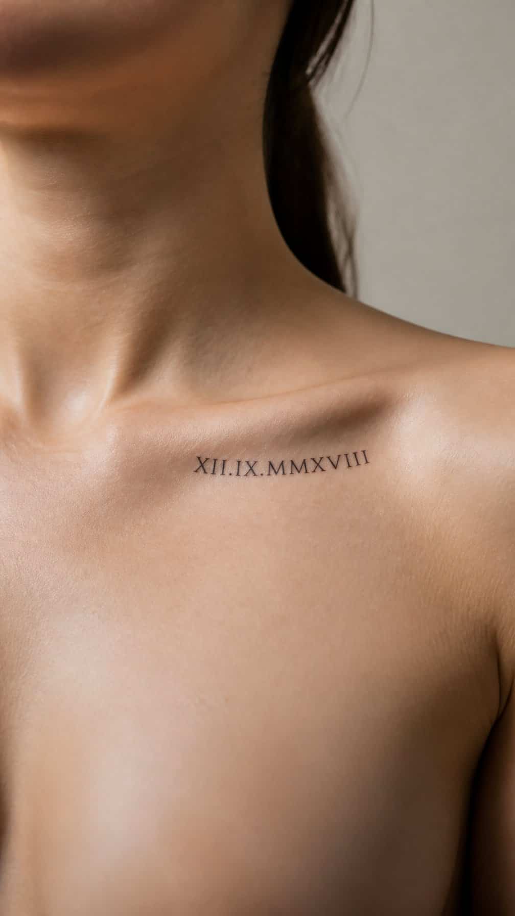 Adult model with a small Roman numeral tattoo beneath the collarbone.