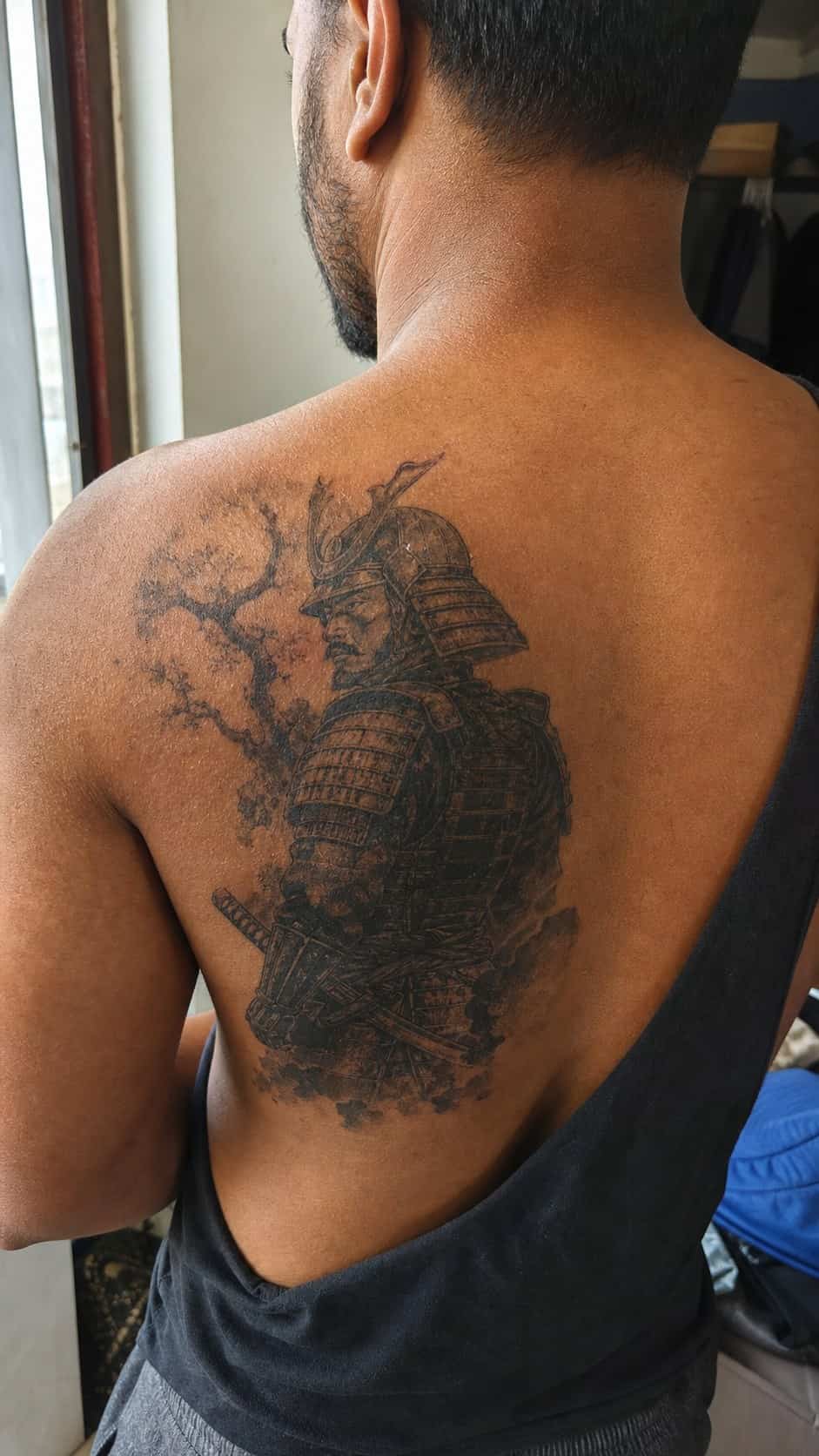 From Samurai to Dragons: 19 Stunning Japanese Tattoo Ideas for Men 4 Healed samurai warrior tattoo on a adult man's upper back, photographed in a natural slightly elevated close view — study 3