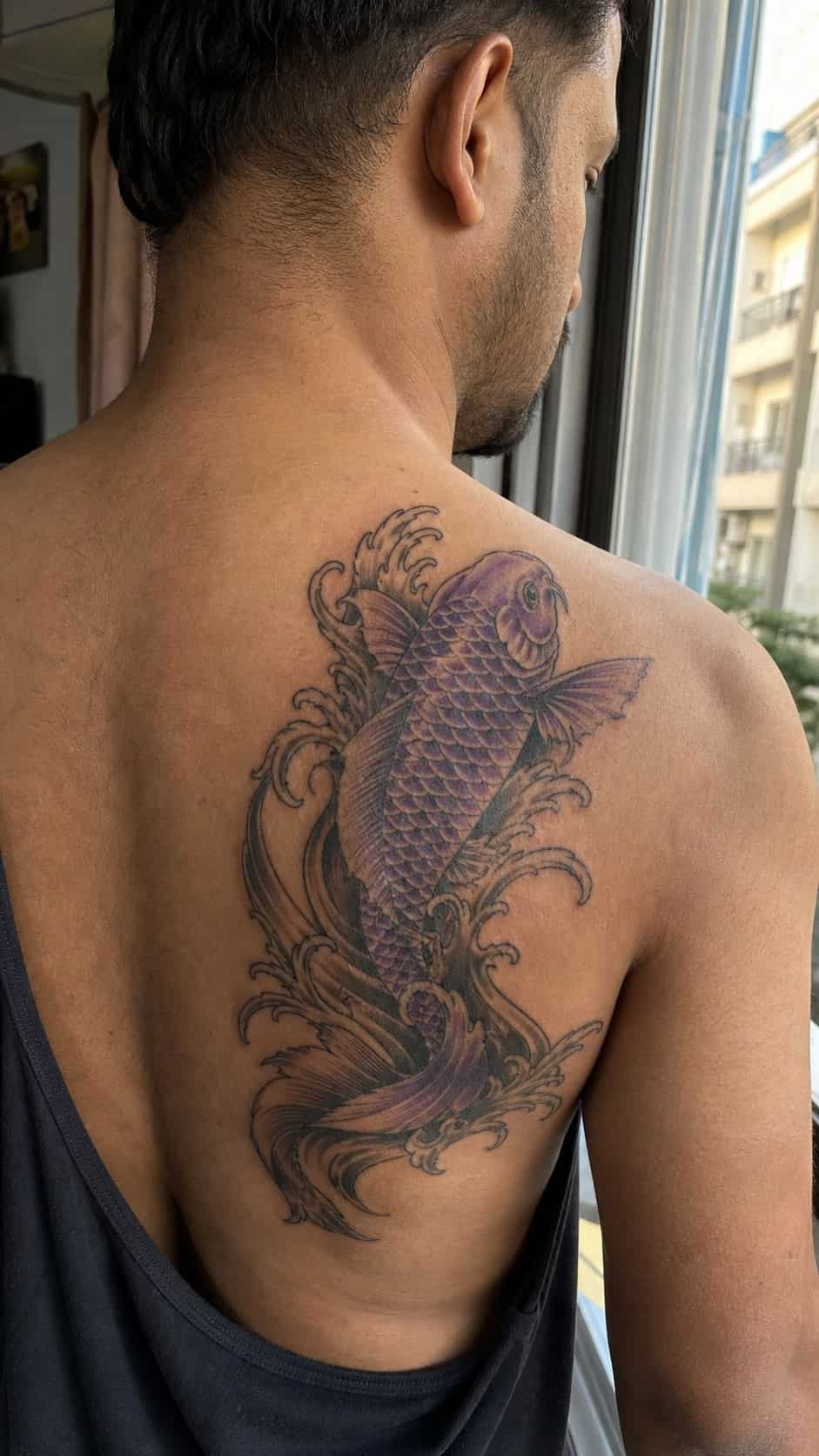 From Samurai to Dragons: 19 Stunning Japanese Tattoo Ideas for Men 6 Healed koi fish tattoo on a adult man's upper back, photographed in a natural gentle side angle that clearly shows how the ink wraps — study 2