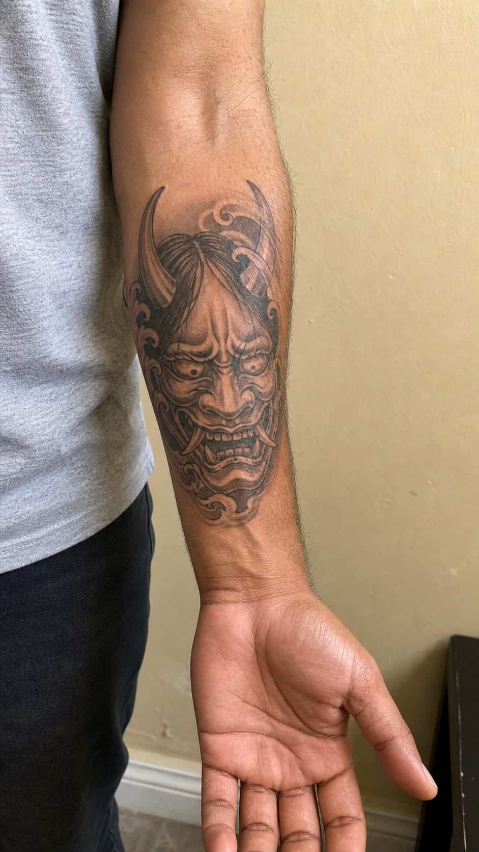 From Samurai to Dragons: 19 Stunning Japanese Tattoo Ideas for Men 12 Healed oni mask tattoo on a adult man's inner forearm, photographed in a natural waist-height candid close-up — study 1