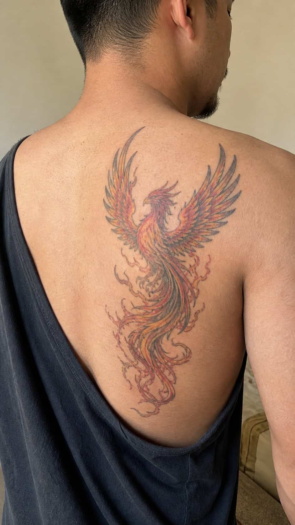 From Samurai to Dragons: 19 Stunning Japanese Tattoo Ideas for Men 14 Healed phoenix tattoo on a adult man's upper back, photographed in a natural casual close three-quarter view — study 1