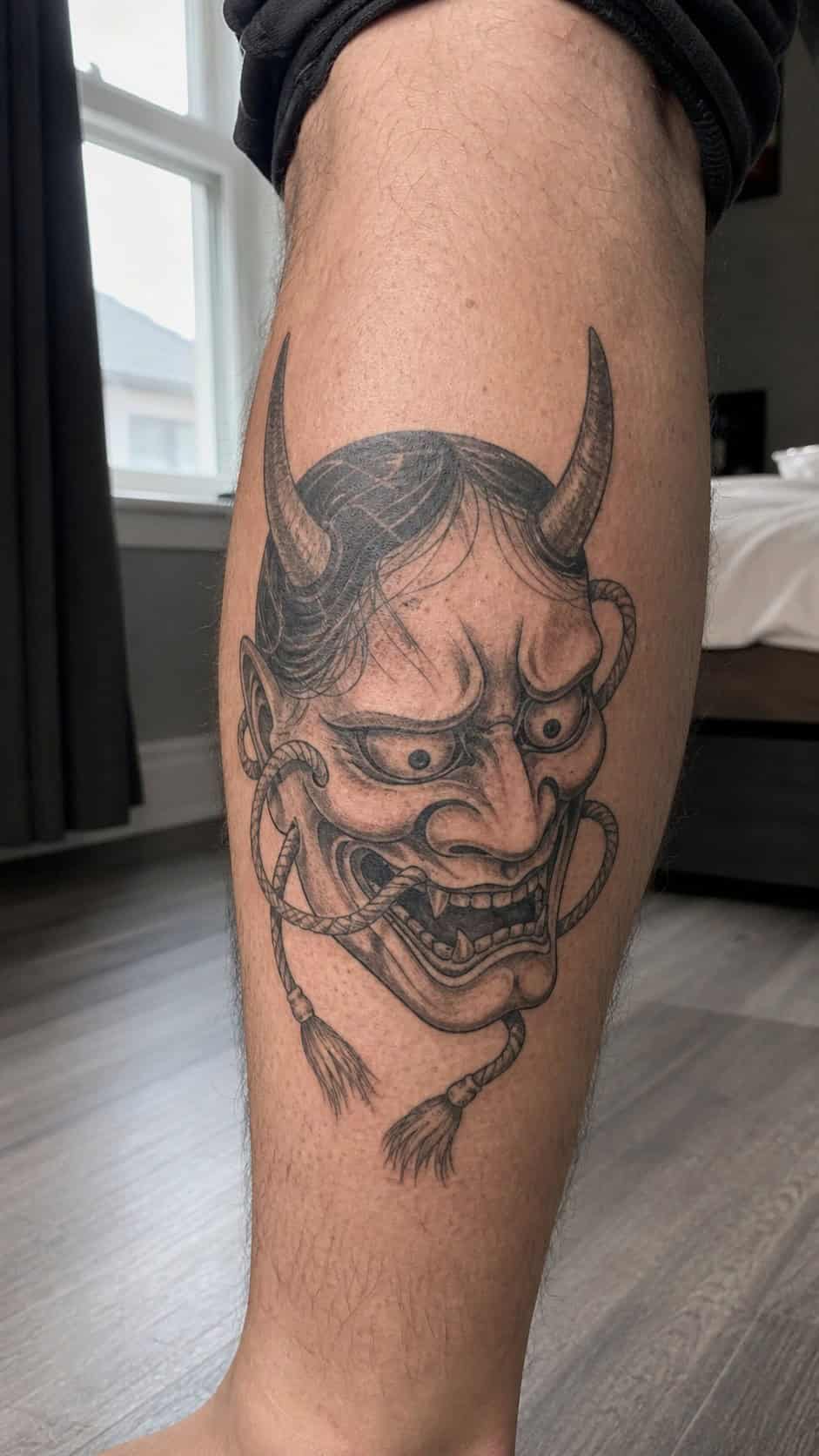 From Samurai to Dragons: 19 Stunning Japanese Tattoo Ideas for Men 16 Healed hannya mask tattoo on a adult man's outer calf, photographed in a natural relaxed documentary crop — study 1