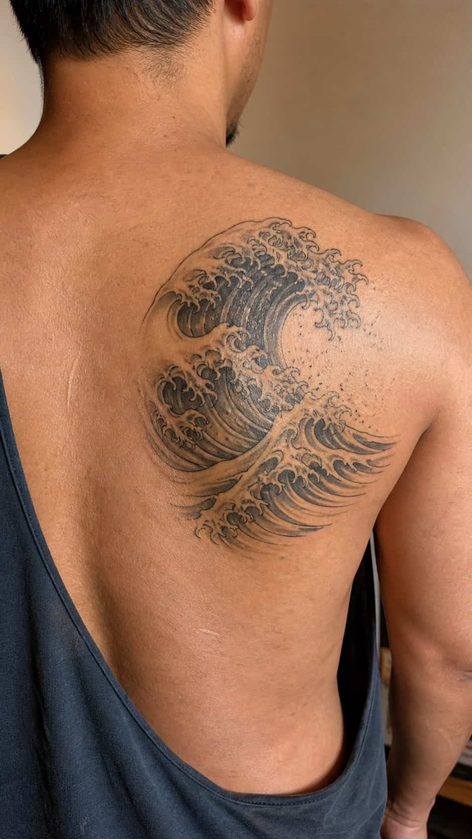 From Samurai to Dragons: 19 Stunning Japanese Tattoo Ideas for Men 22 Healed wave patterns tattoo on a adult man's upper back, photographed in a natural slightly elevated close view — study 2