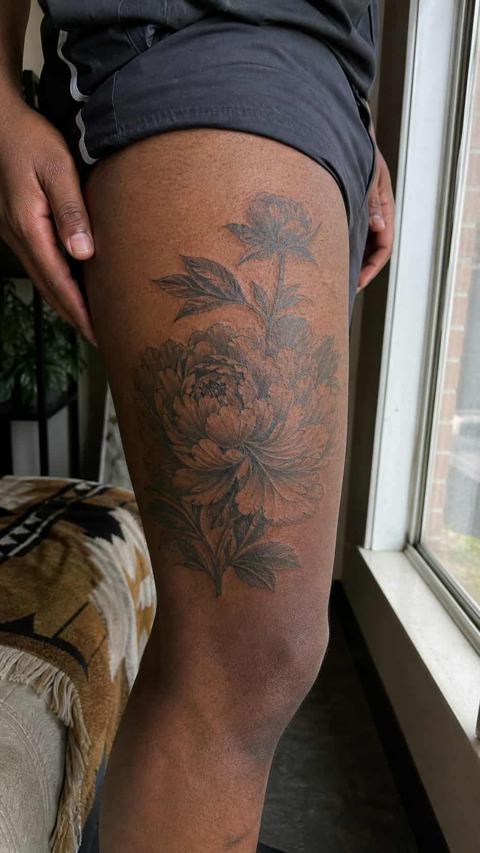 From Samurai to Dragons: 19 Stunning Japanese Tattoo Ideas for Men 34 Healed peony tattoo on a adult man's outer thigh, photographed in a natural casual close three-quarter view — study 1