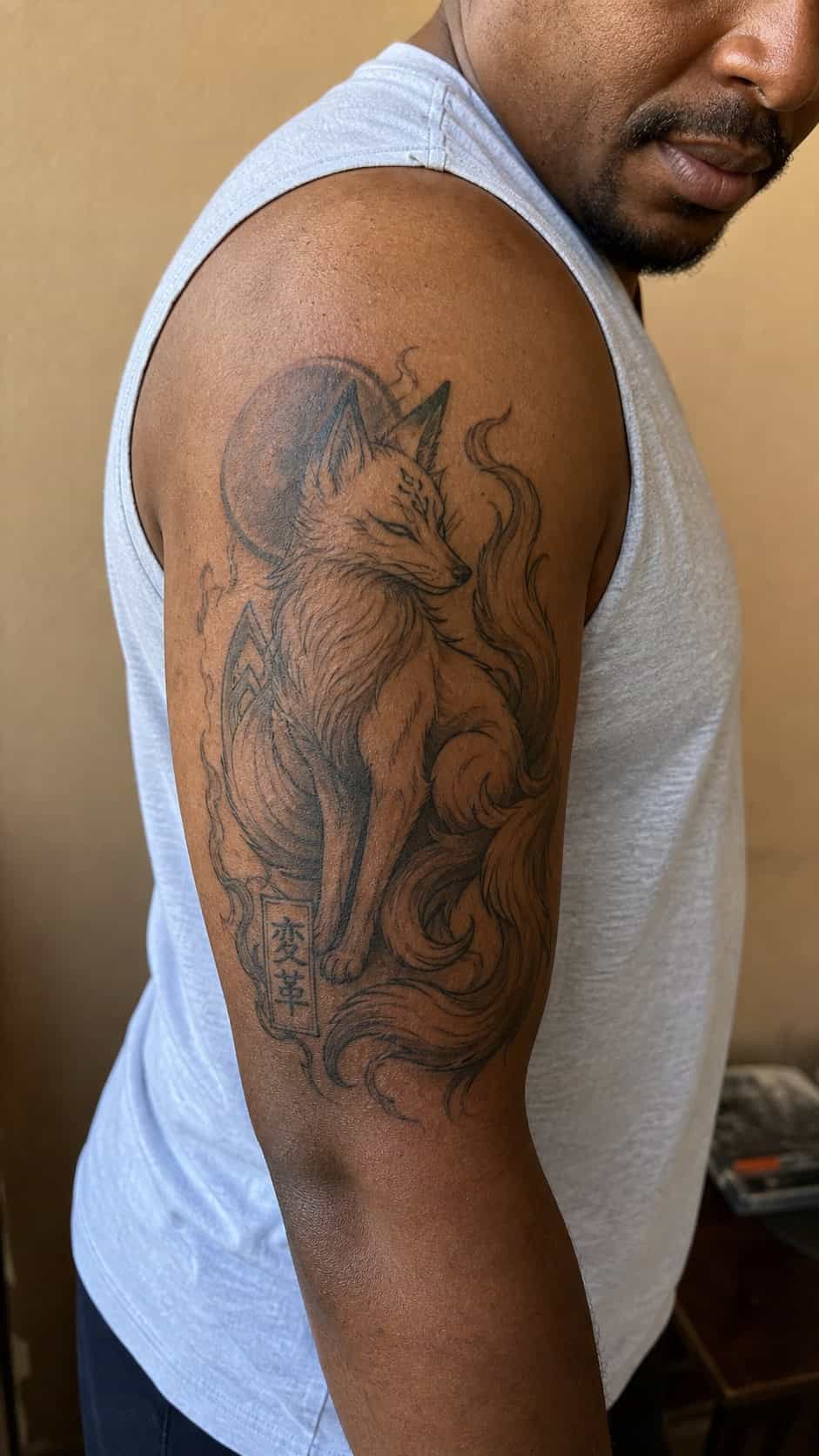 From Samurai to Dragons: 19 Stunning Japanese Tattoo Ideas for Men 36 Healed kitsune (fox) tattoo on a adult man's outer upper arm, photographed in a natural waist-height candid close-up — study 1