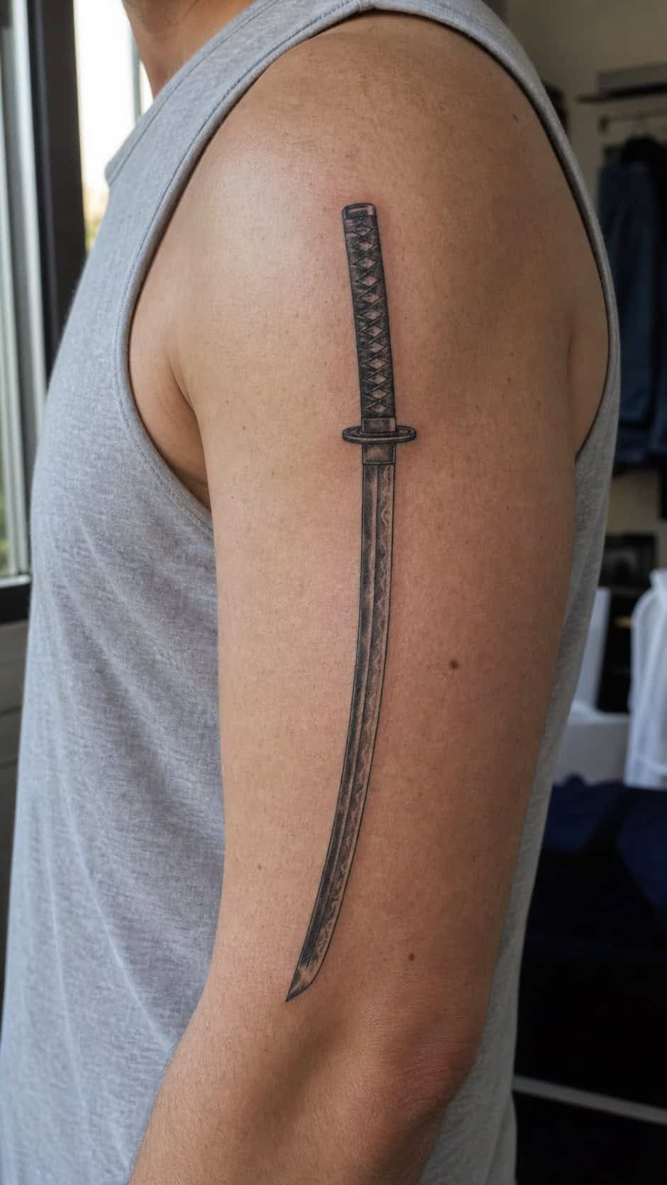 From Samurai to Dragons: 19 Stunning Japanese Tattoo Ideas for Men 39 Healed samurai sword (katana) tattoo on a adult man's outer upper arm, photographed in a natural slightly elevated close view — study 1