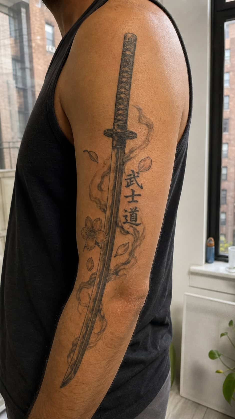 From Samurai to Dragons: 19 Stunning Japanese Tattoo Ideas for Men 40 Healed samurai sword (katana) tattoo on a adult man's outer upper arm, photographed in a natural waist-height candid close-up — study 2