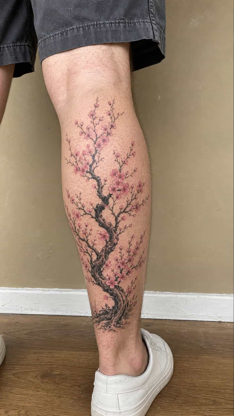 From Samurai to Dragons: 19 Stunning Japanese Tattoo Ideas for Men 45 Healed cherry blossom tree tattoo on a adult man's outer calf, photographed in a natural slightly elevated close view — study 2