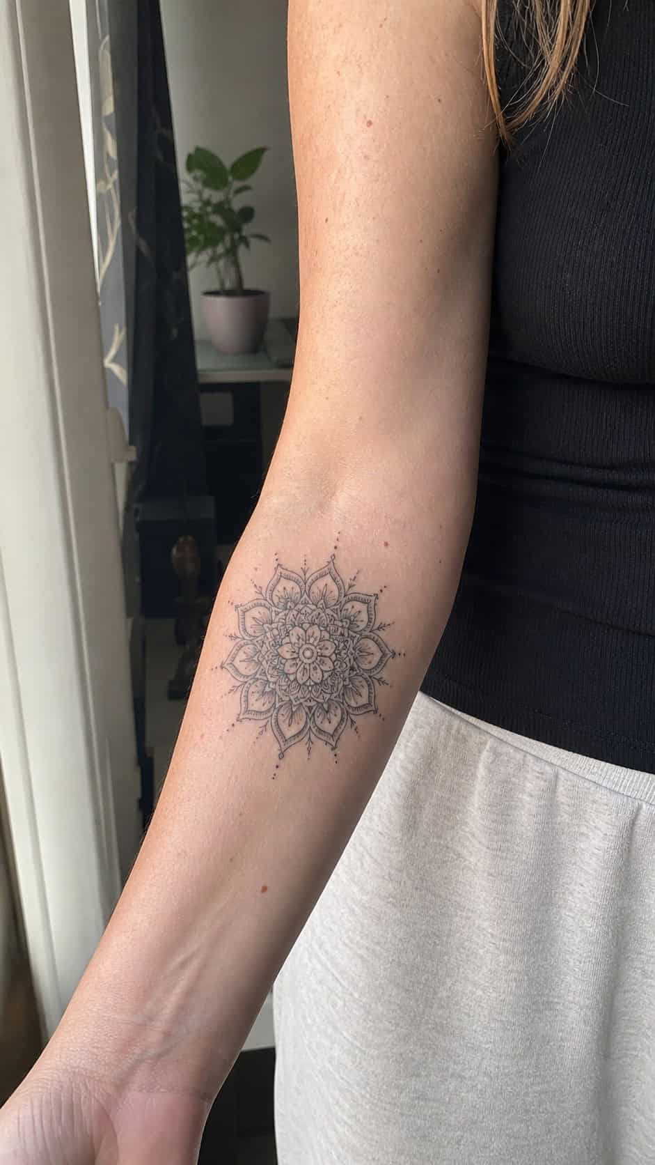 Healed delicate mandala pattern tattoo on a adult woman's inner forearm, photographed in a natural slightly elevated close view — study 2