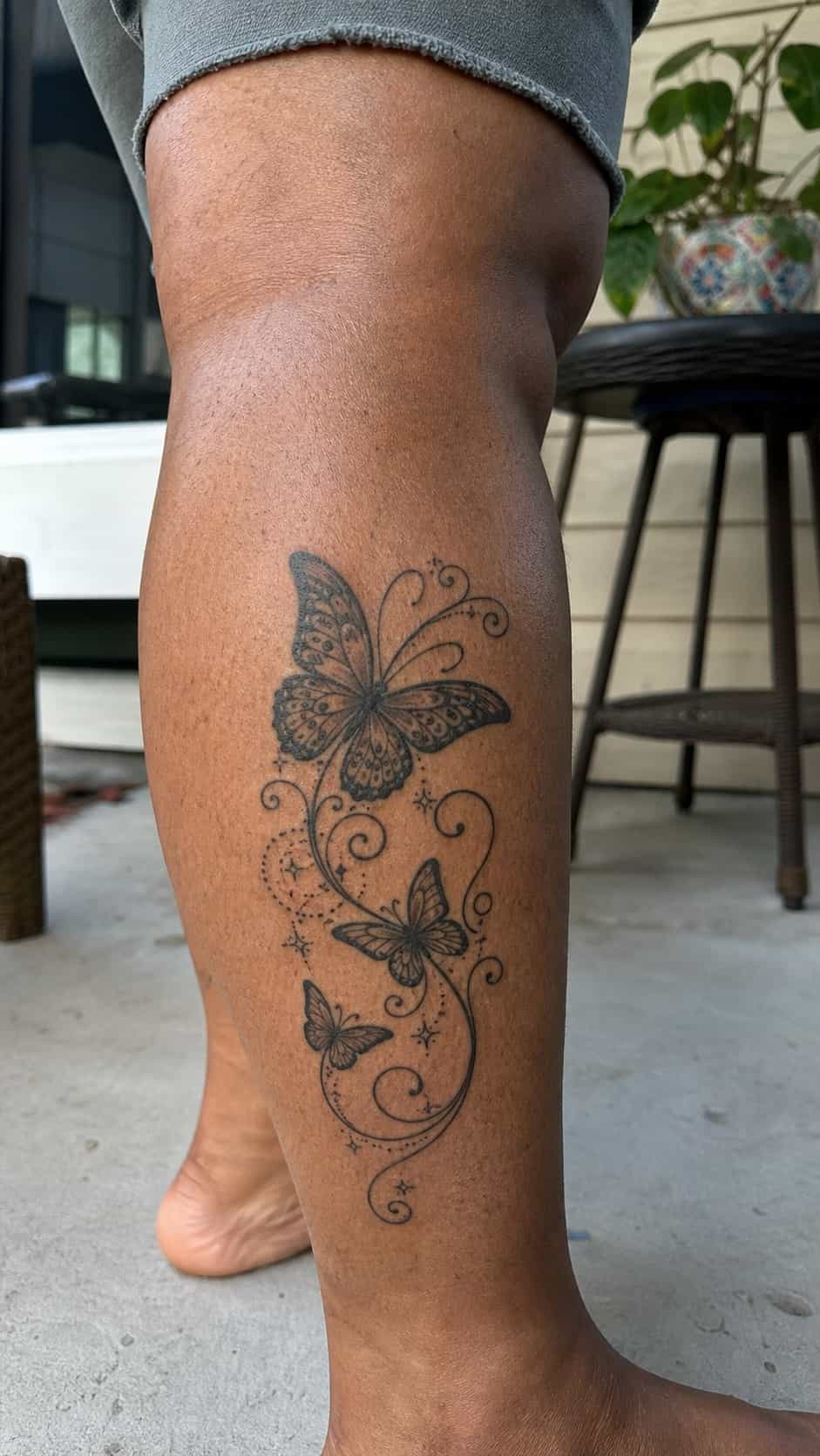 Healed whimsical butterfly design tattoo on a adult woman's outer calf, photographed in a natural gentle side angle that clearly shows — study 1