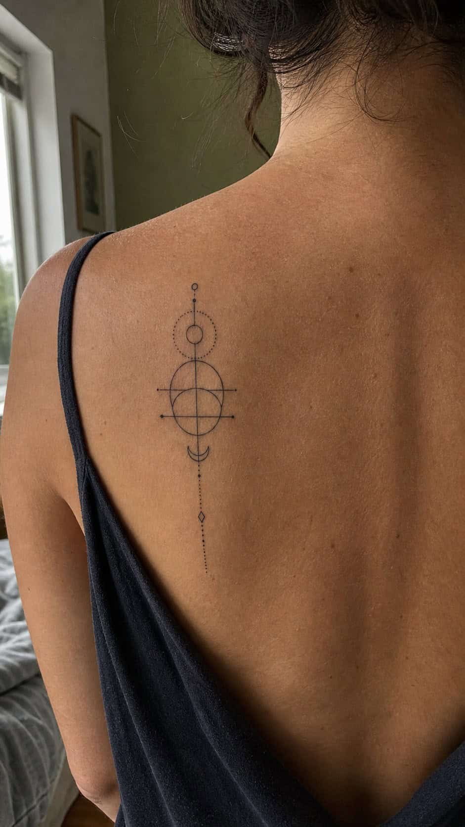 Healed geometric minimalism tattoo on a adult woman's upper back, photographed in a natural straight-on close view, a touch off-center — study 1