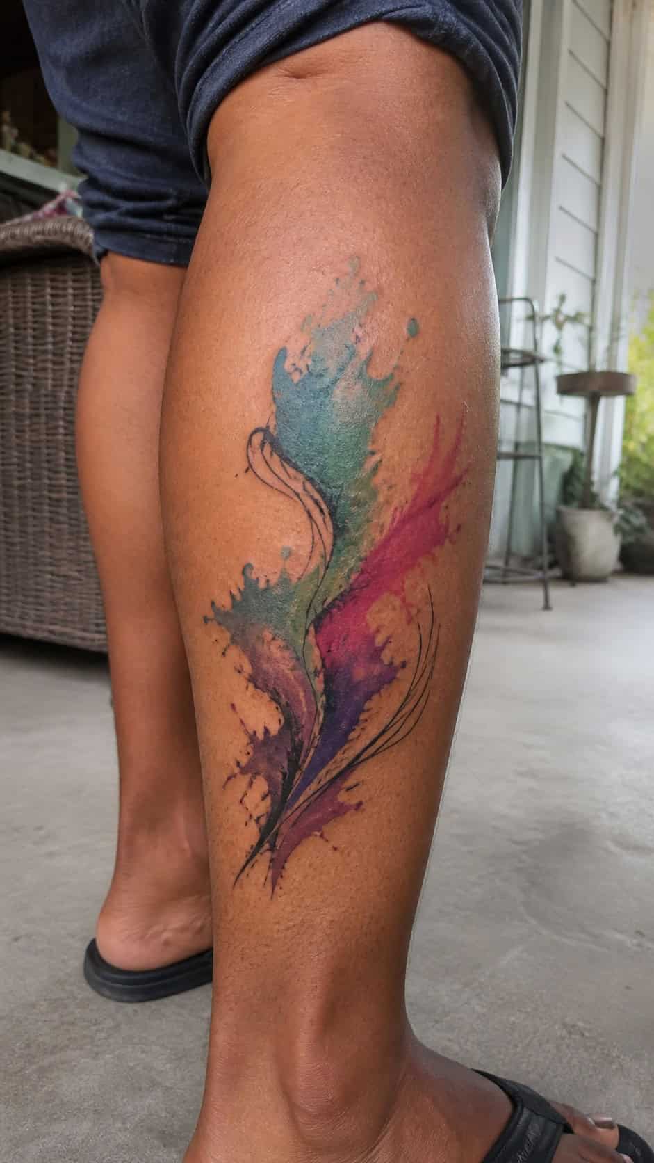 Healed artistic watercolor splash tattoo on a adult woman's outer calf, photographed in a natural straight-on close view, a touch — study 2