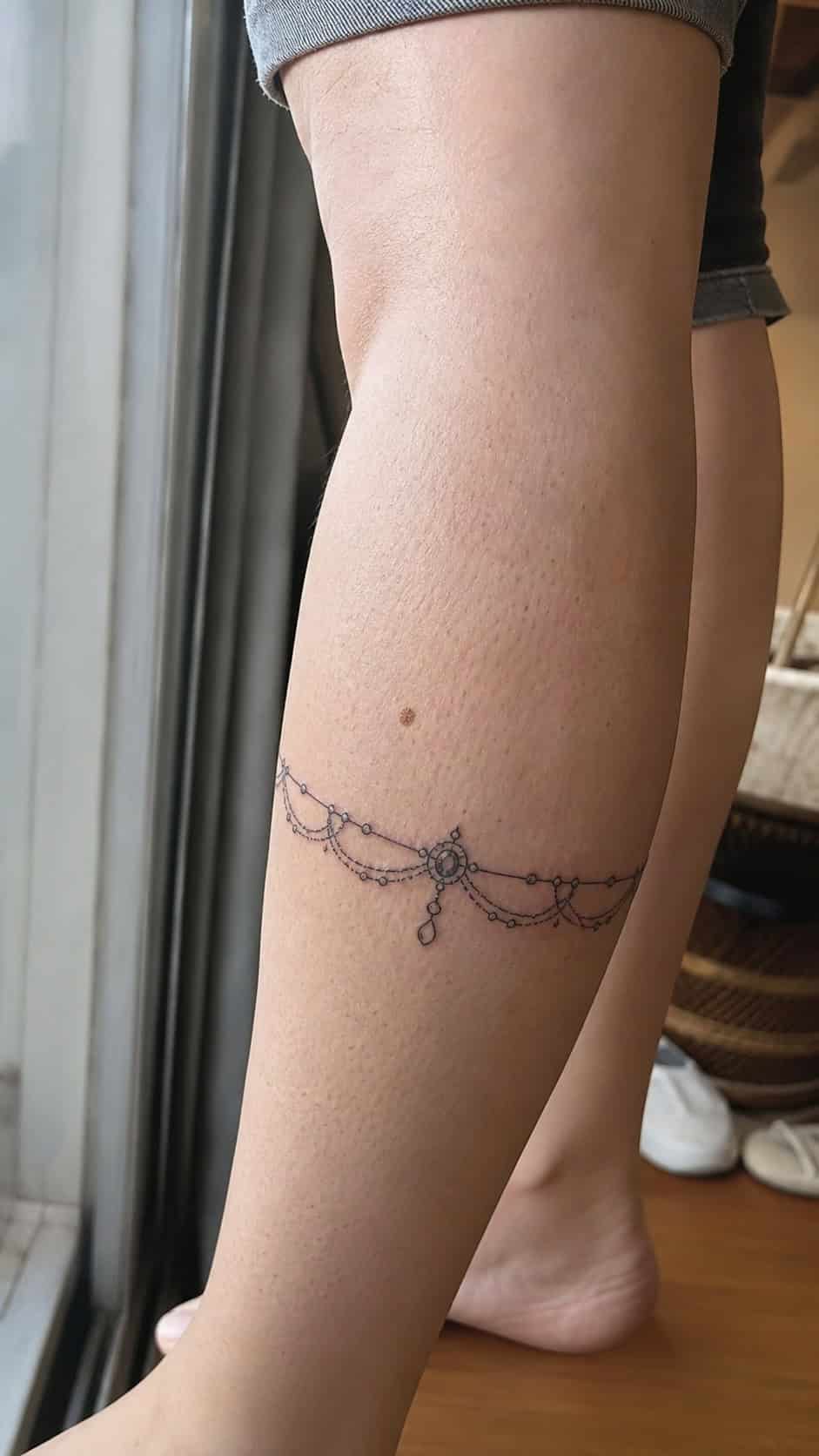 Healed chic bracelet design tattoo on a adult woman's outer calf, photographed in a natural gentle side angle that clearly shows how — study 2