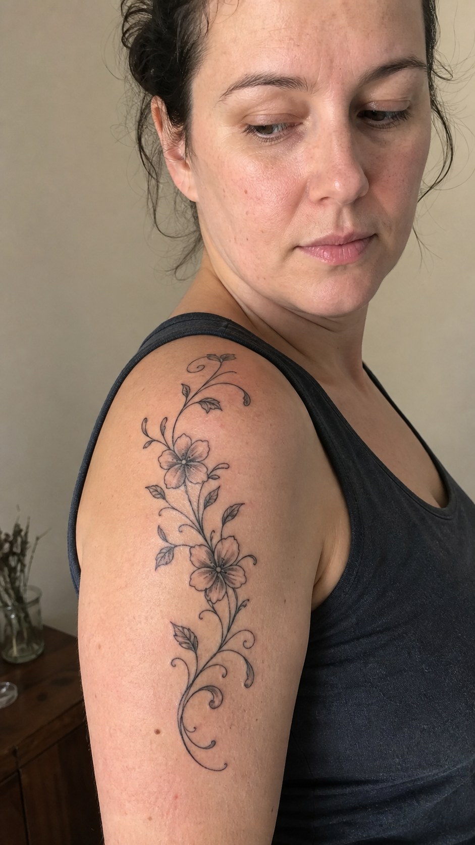 Healed graceful floral vine tattoo on a adult woman's shoulder, photographed in a natural waist-height candid close-up — study 1