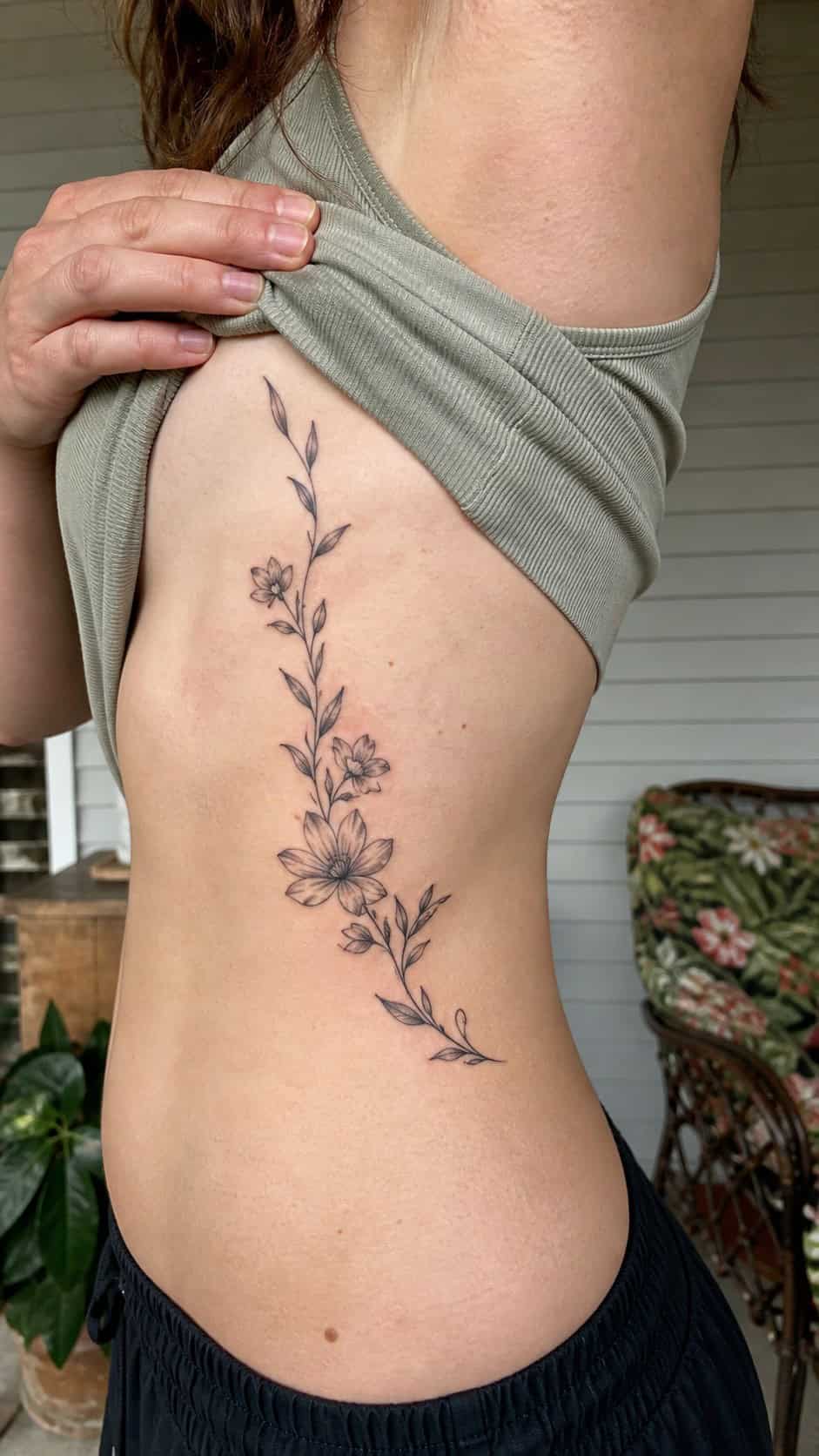 32 Stunning Rib Tattoos for Women 3 Healed floral vine elegance tattoo on a adult woman's side ribs, photographed in a natural casual close three-quarter view — study 2