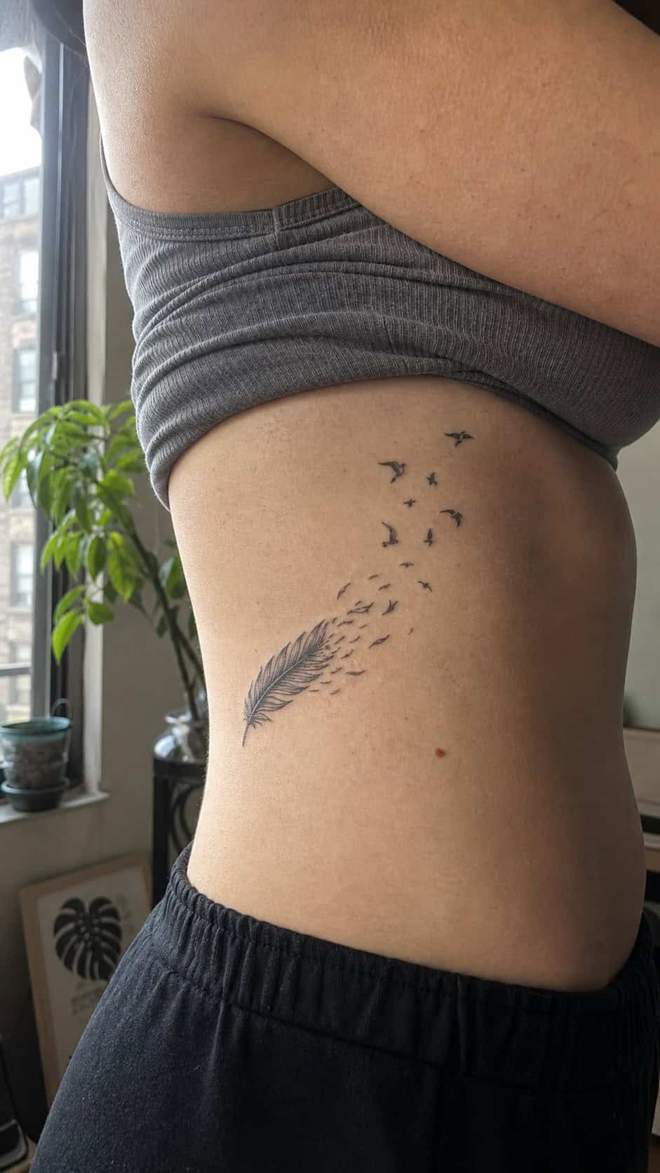 32 Stunning Rib Tattoos for Women 6 Healed feather in the wind tattoo on a adult woman's side ribs, photographed in a natural straight-on close view, a touch off-center — study 1
